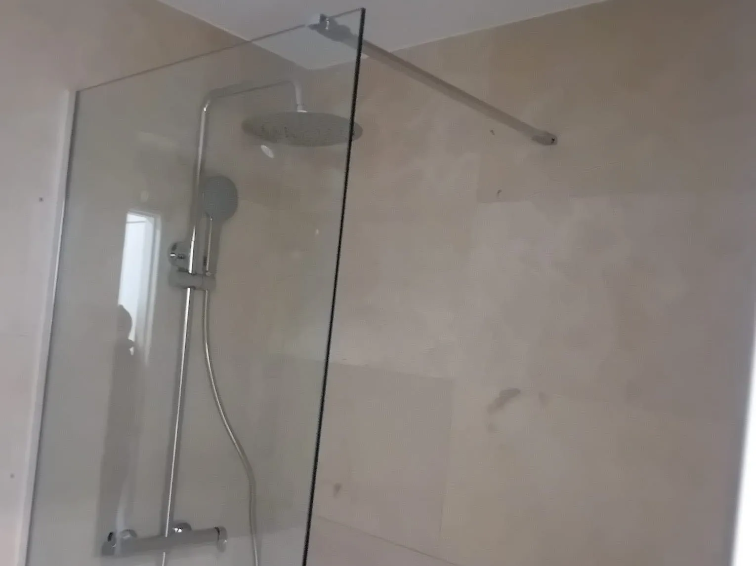 Ducha con mampara fija y columna termostática con rociador de lluvia, en un baño de MS Reformas