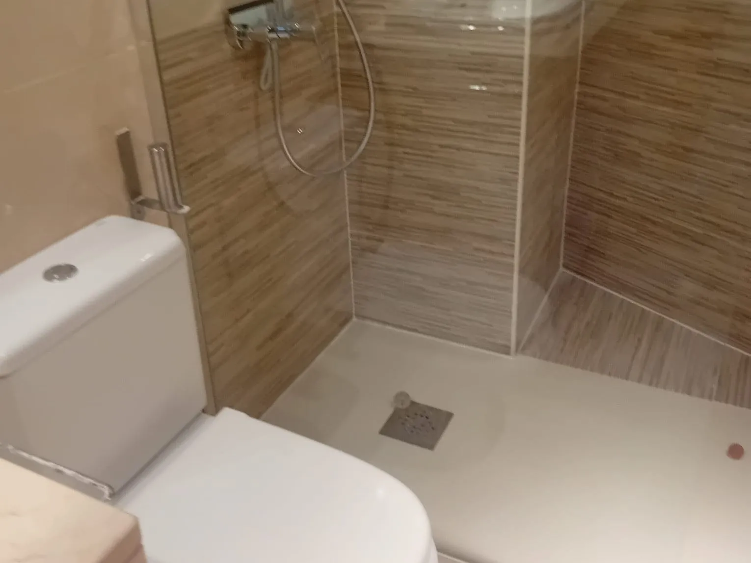 Baño reformado por MS Reformas: plato de ducha, mampara de cristal y alicatado imitación madera