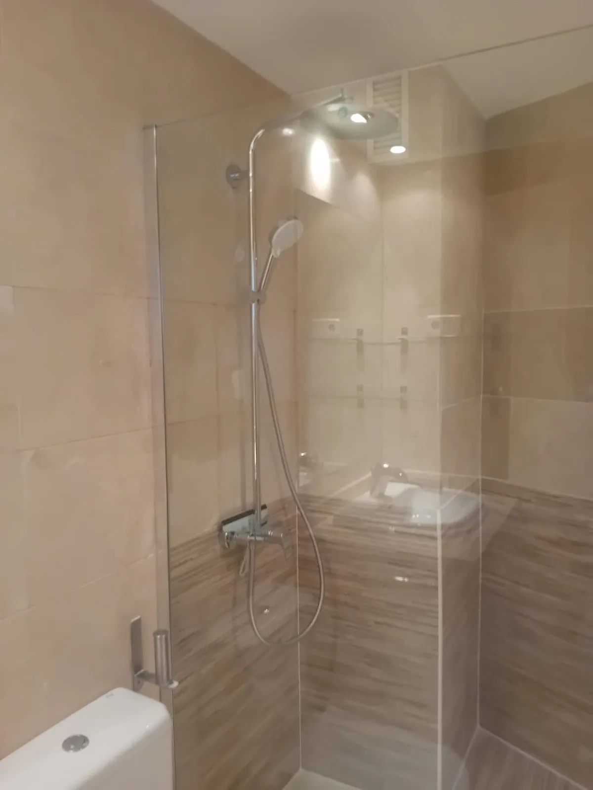 Ducha con columna, mampara de cristal y alicatado en dos tonos
