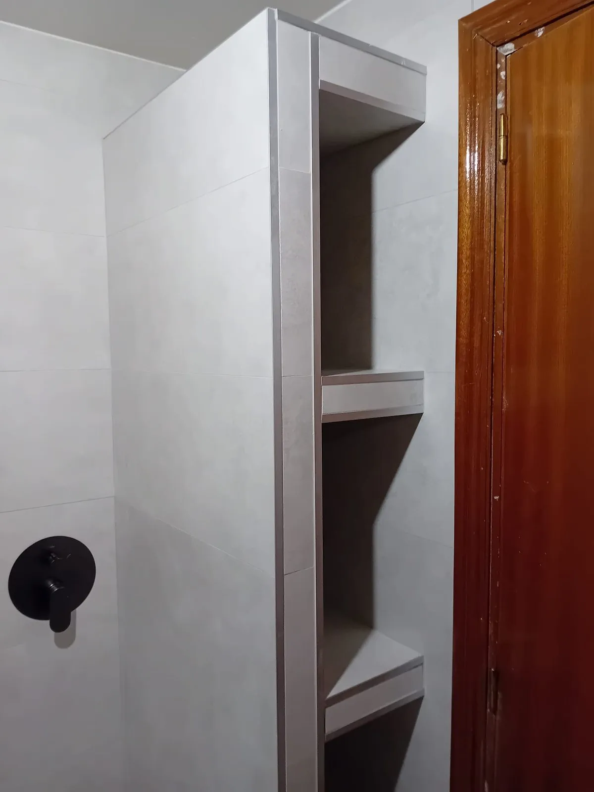 Hornacina de obra con baldas dentro de la ducha y grifo empotrado en negro